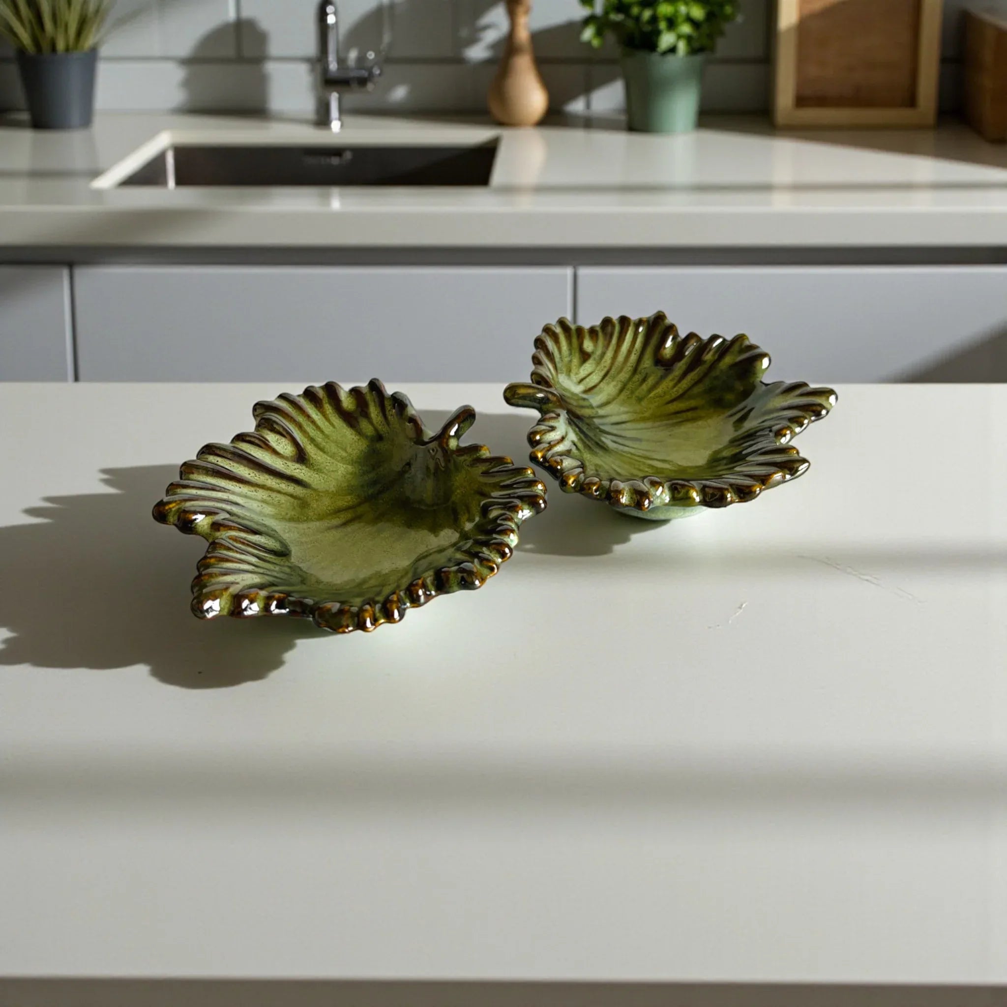 Two green ceramic leaf-shaped dishes on a kitchen counter.