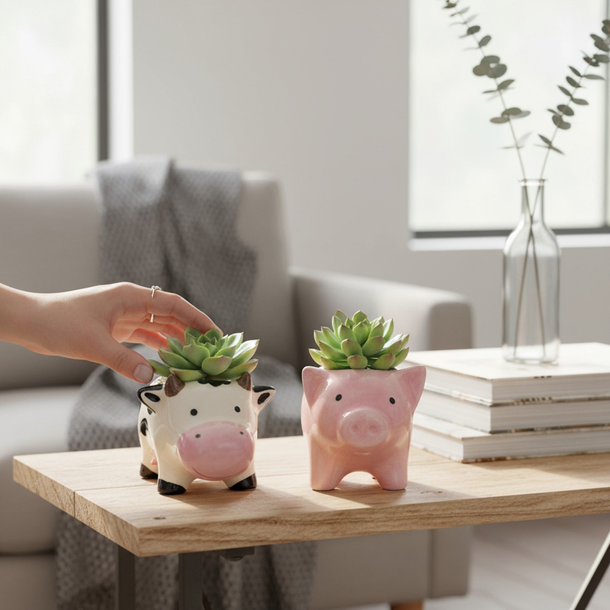 Two small ceramic planters shaped like a cow and a pig on a wooden coffee table.