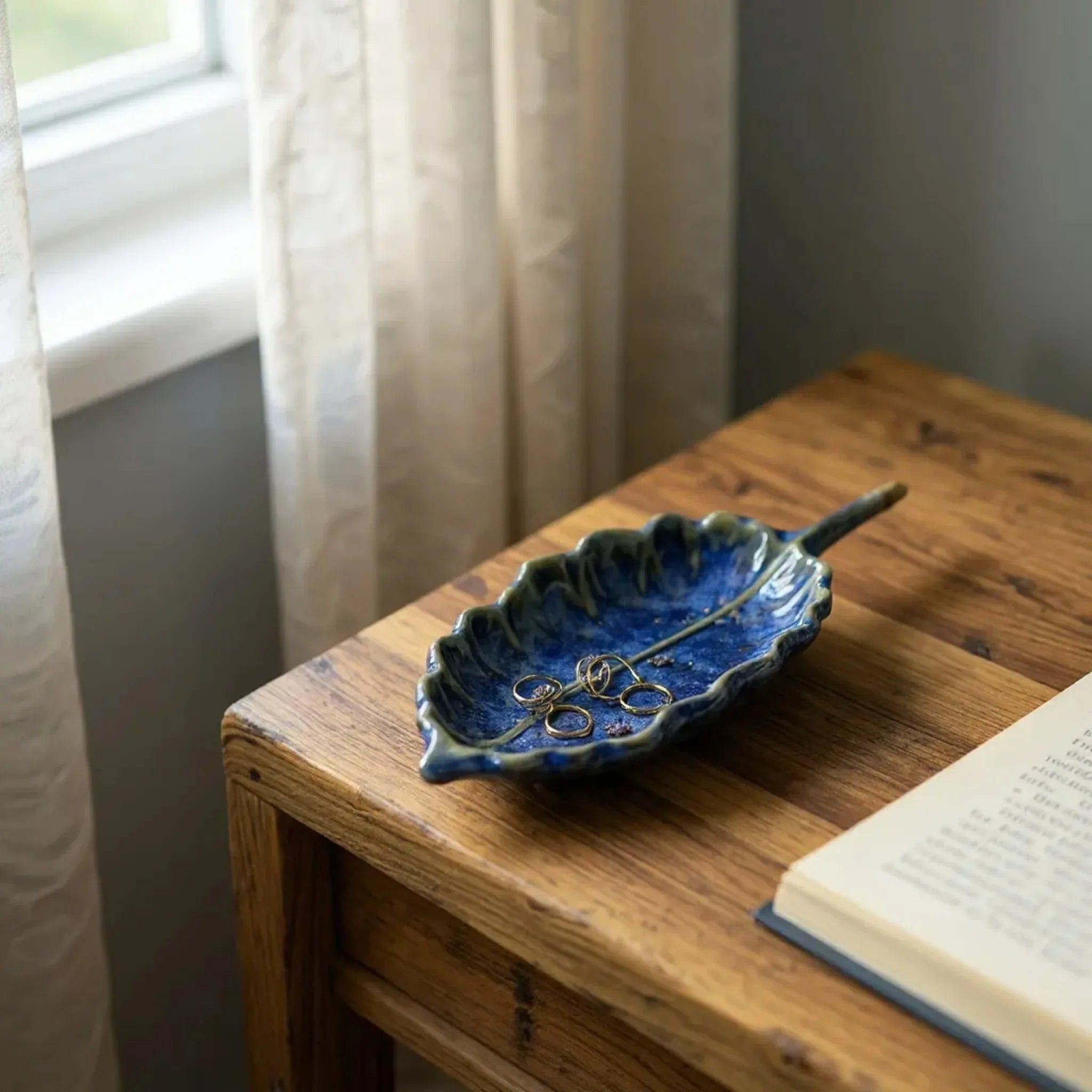 Bedside organization; the leaf dishes holding a gold rings, and earrings on a wooden nightstand.