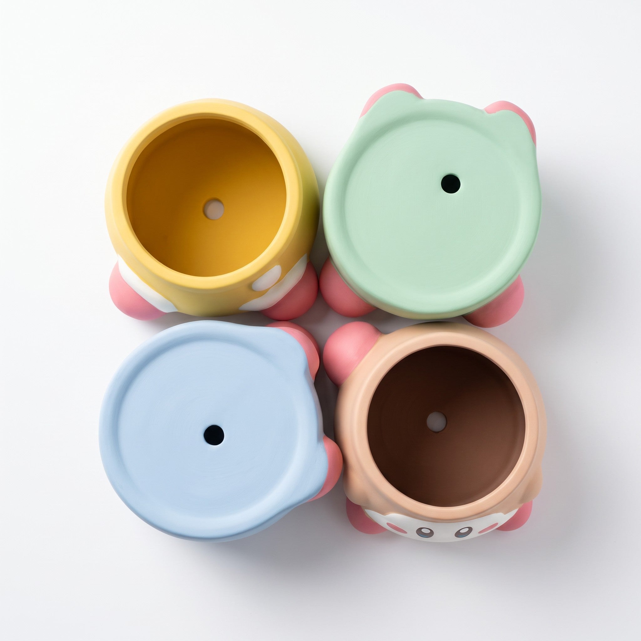 Four small character-shaped planters arranged in a 2x2 grid on a white background. Each planter has a round lid with a hole and a colorful body, shown from above.