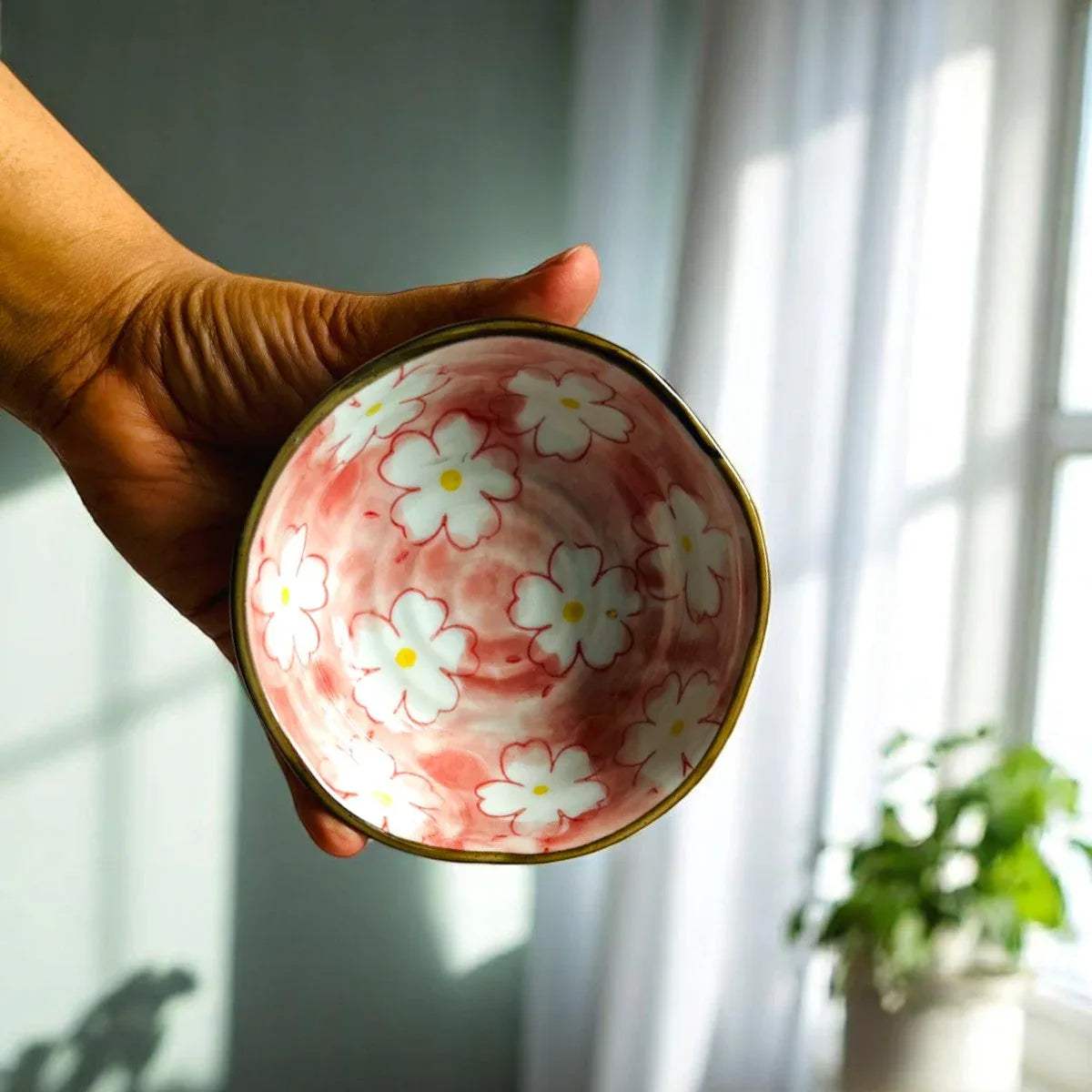 Hand holding the bowl highlighting the intricate petal details and the smooth, reflective porcelain glaze.