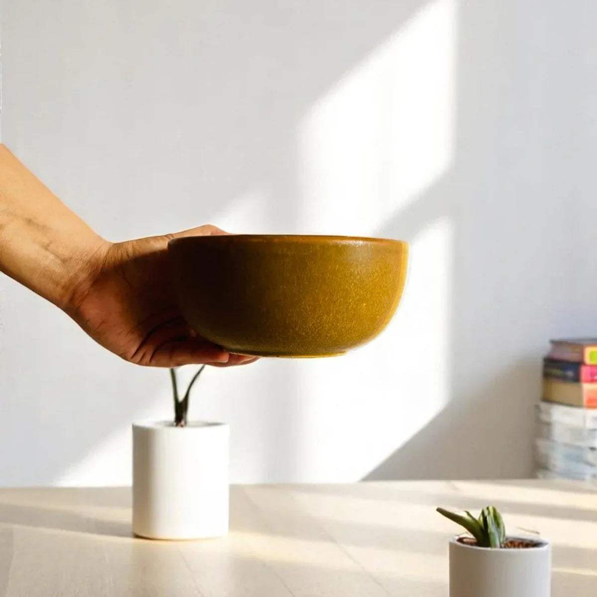 Hand holding a rustic stoneware bowl in natural light, minimalist tableware by Rustic Stone.