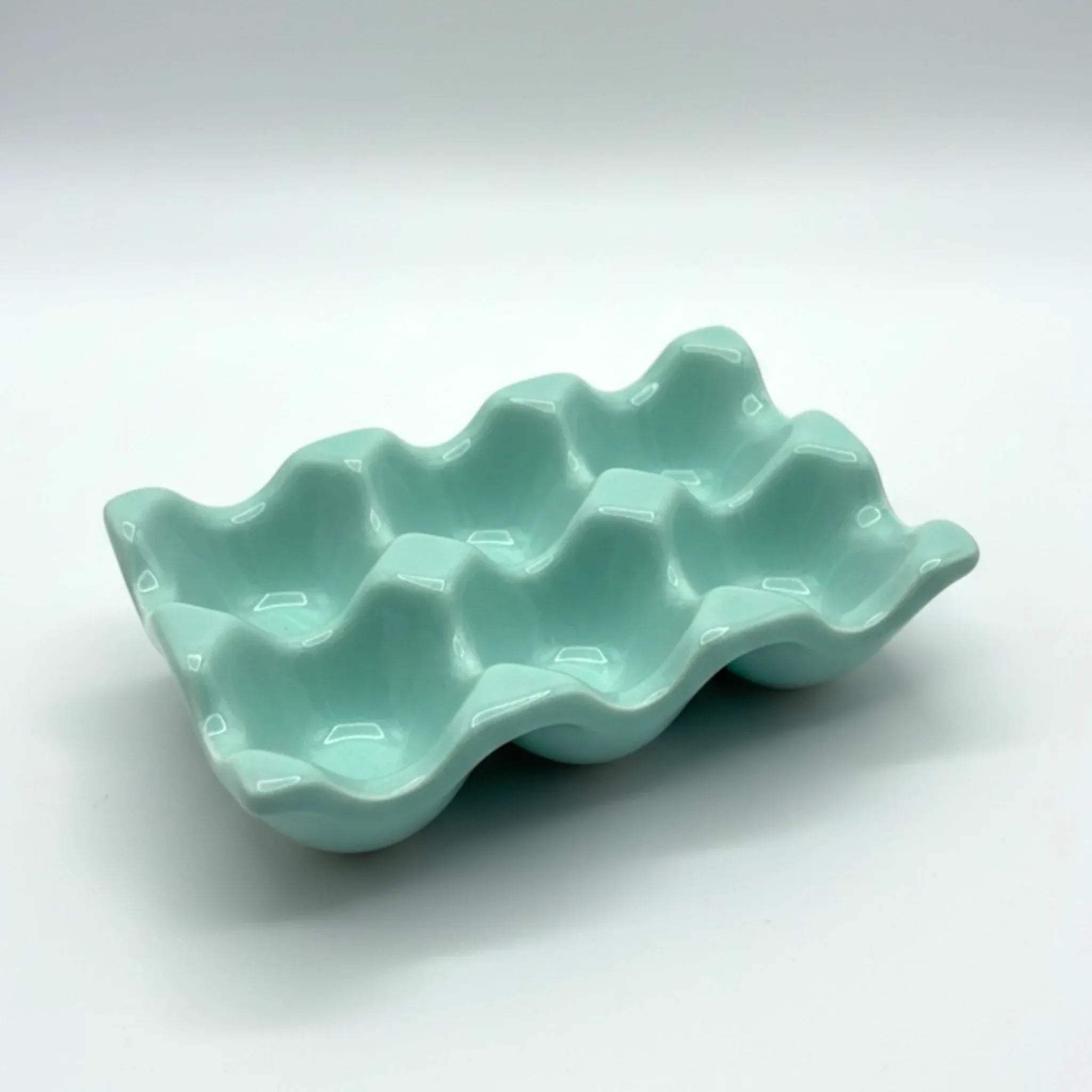 Smooth sea green ceramic glaze; scalloped 6-egg holder details and artisanal pottery finish for mood boards.