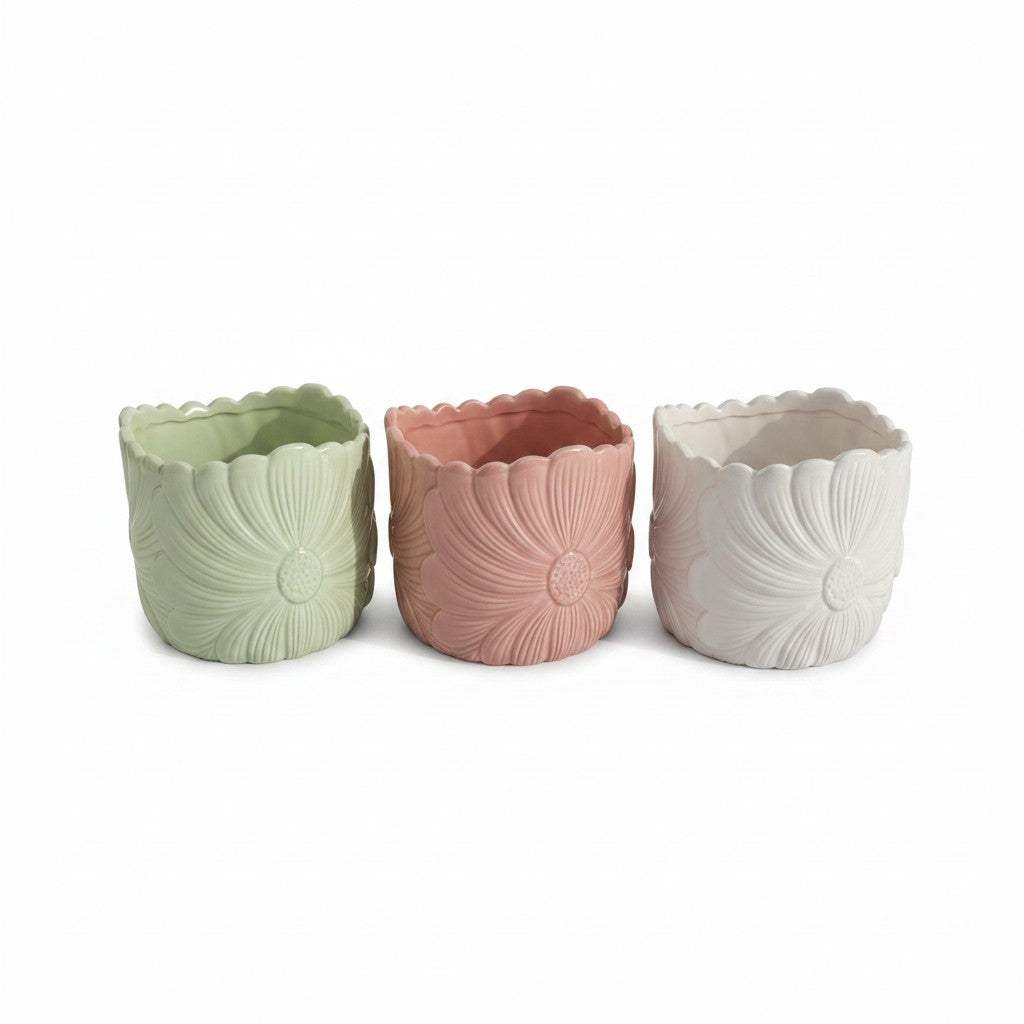 Close-up view of the detailed embossed flower petal pattern and glossy glaze finish on the pastel pink ceramic planter.