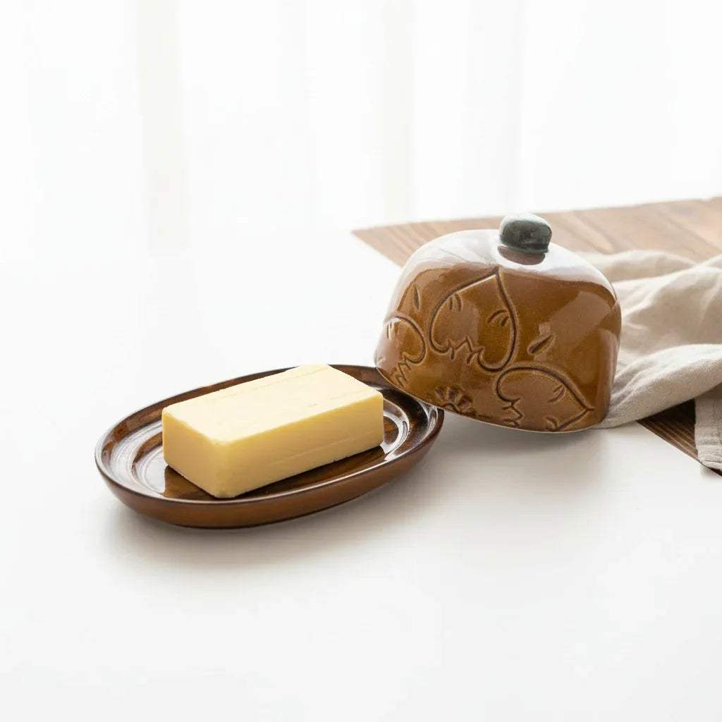 Detailed shot of etched surface; intricate floral patterns on a warm amber ceramic glaze with a blue-grey knob.