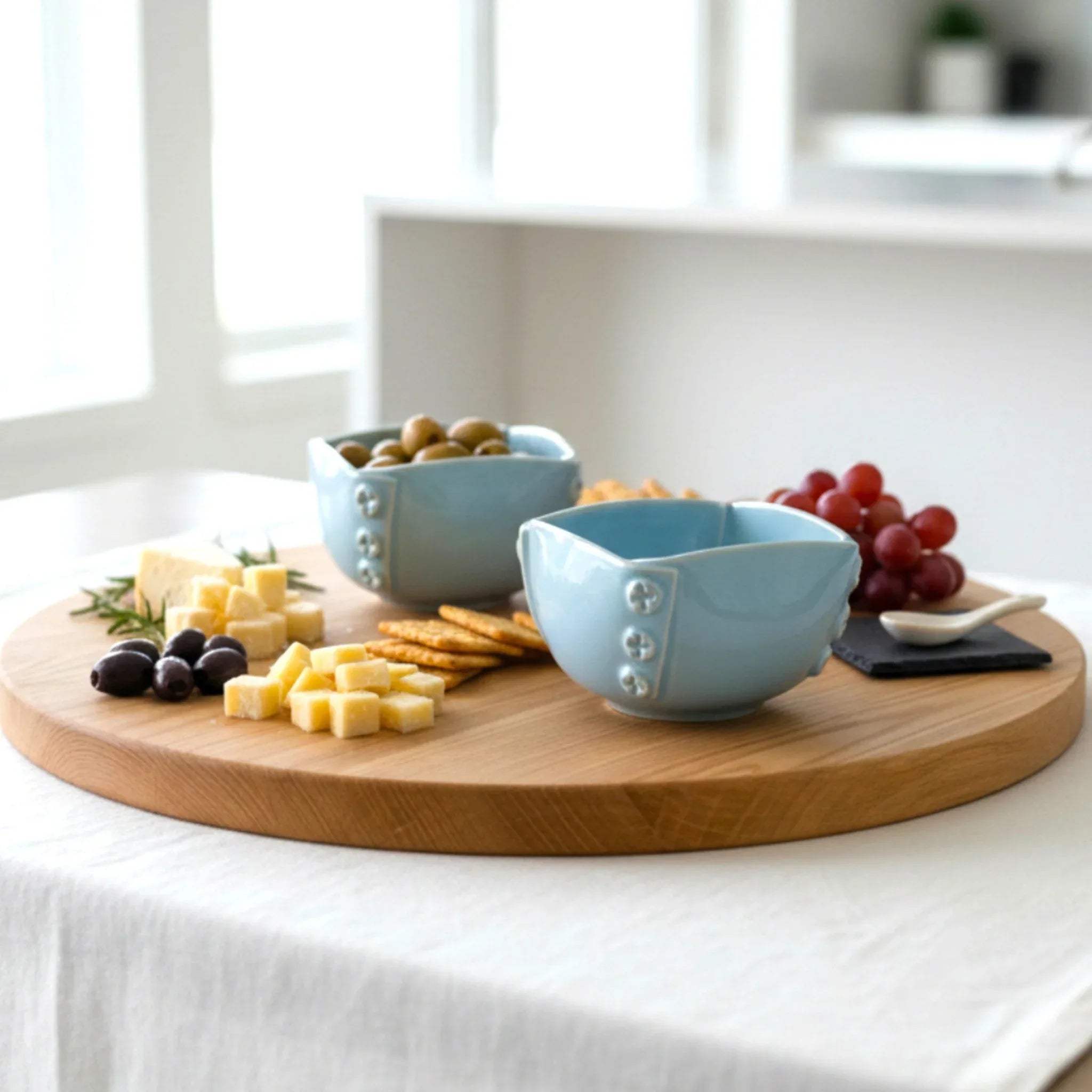 Appetizer spread; the mini bowls holding colorful dips like beetroot hummus and pesto on a rustic wooden board.