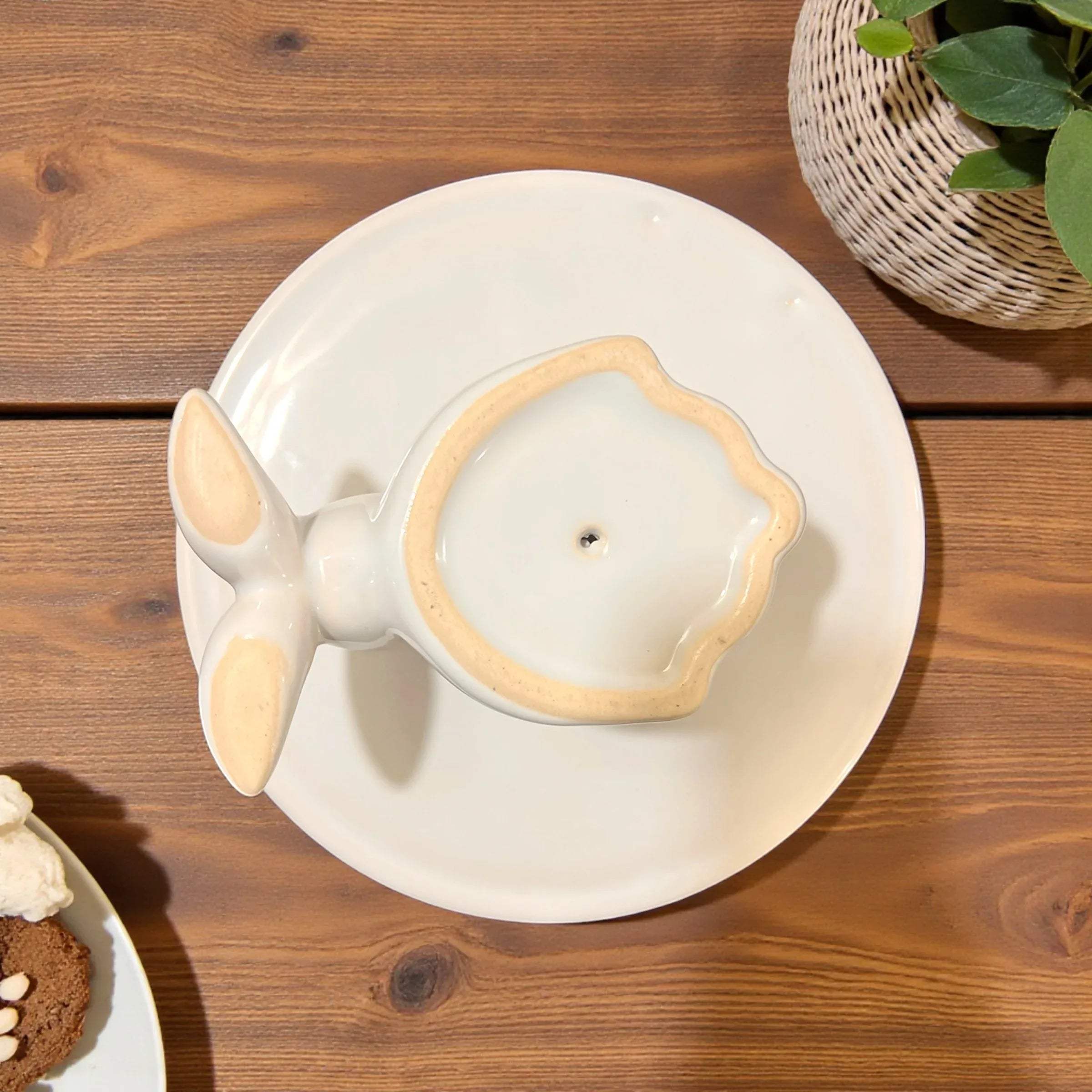 Bottom view of the cake stand; handcrafted white ceramic finish and smooth pedestal surface for cakes.