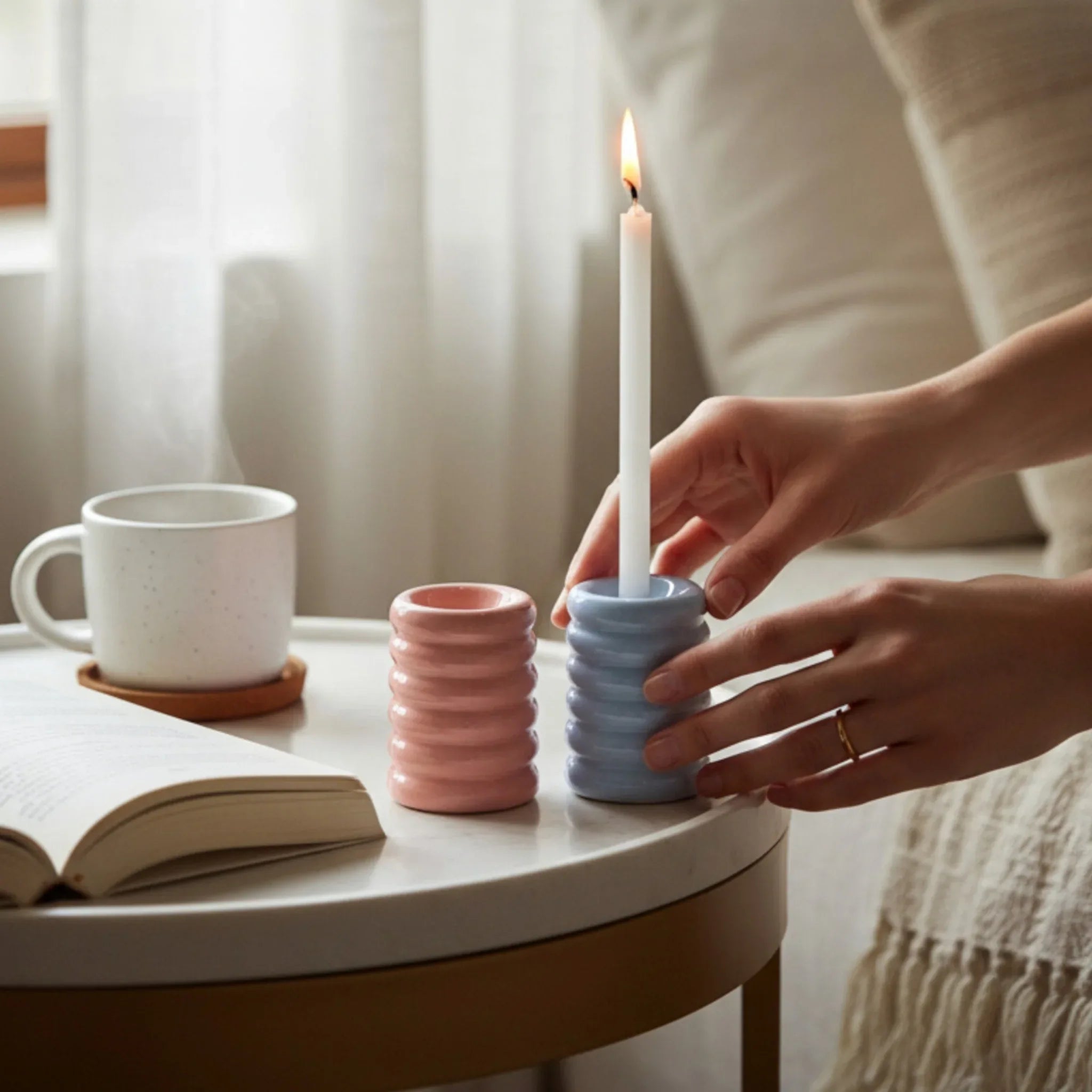 Hand touching the holders next to a mug; compact pair ideal for dining tables, windowsills, or coffee table accents.