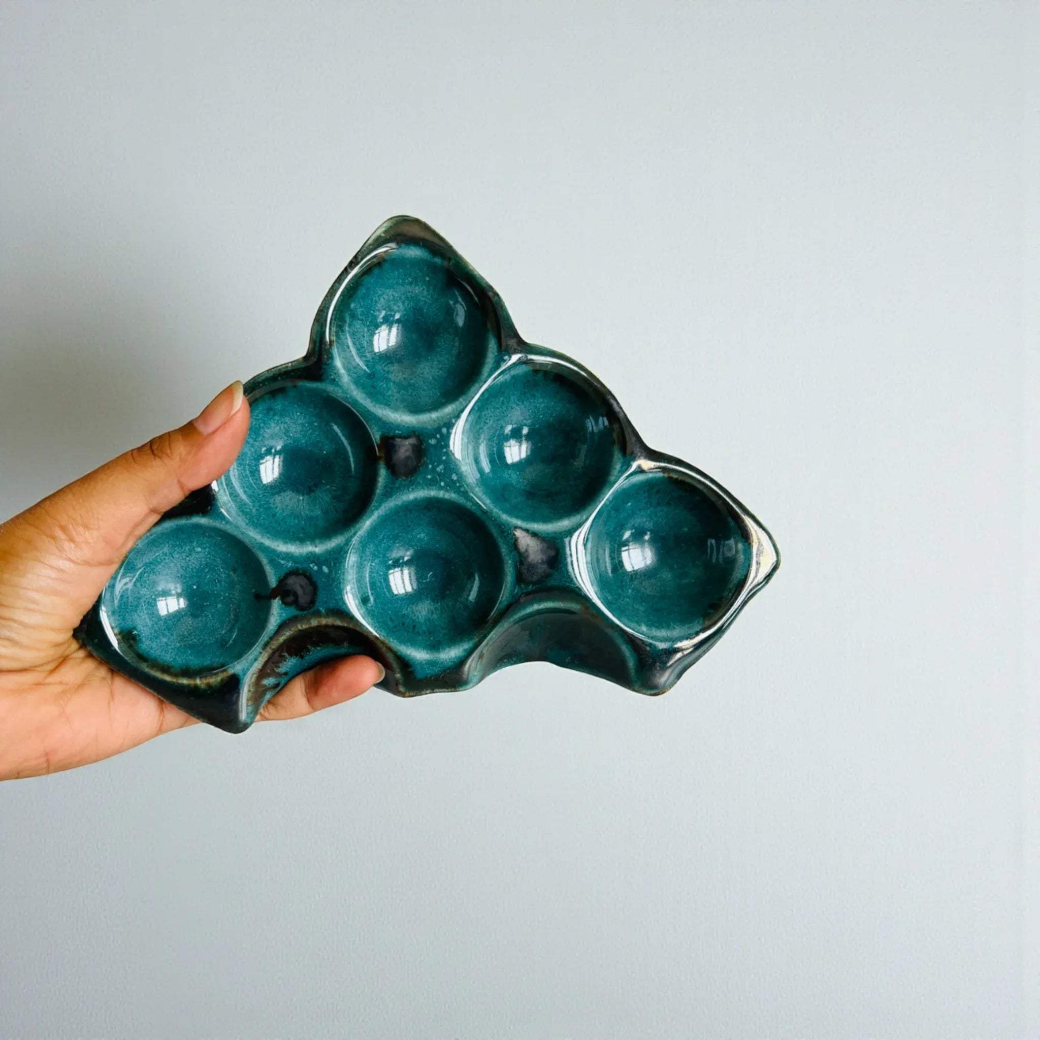 Hand holding an egg into the 6-inch Ocean Mirage tray; demonstrating the compact and stable design.