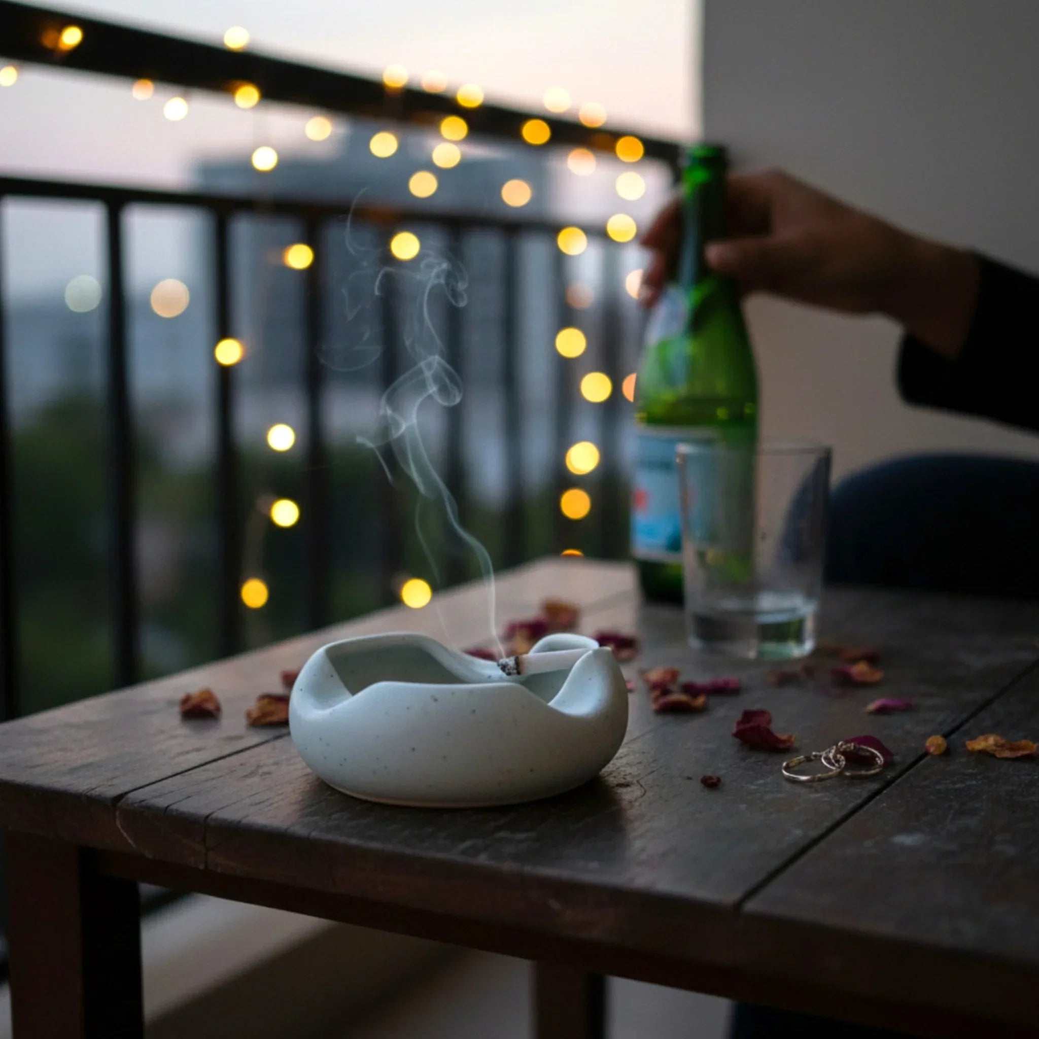 Outdoor balcony scene; the wind-resistant heavy stone ashtray styled with minimalist slate coasters.
