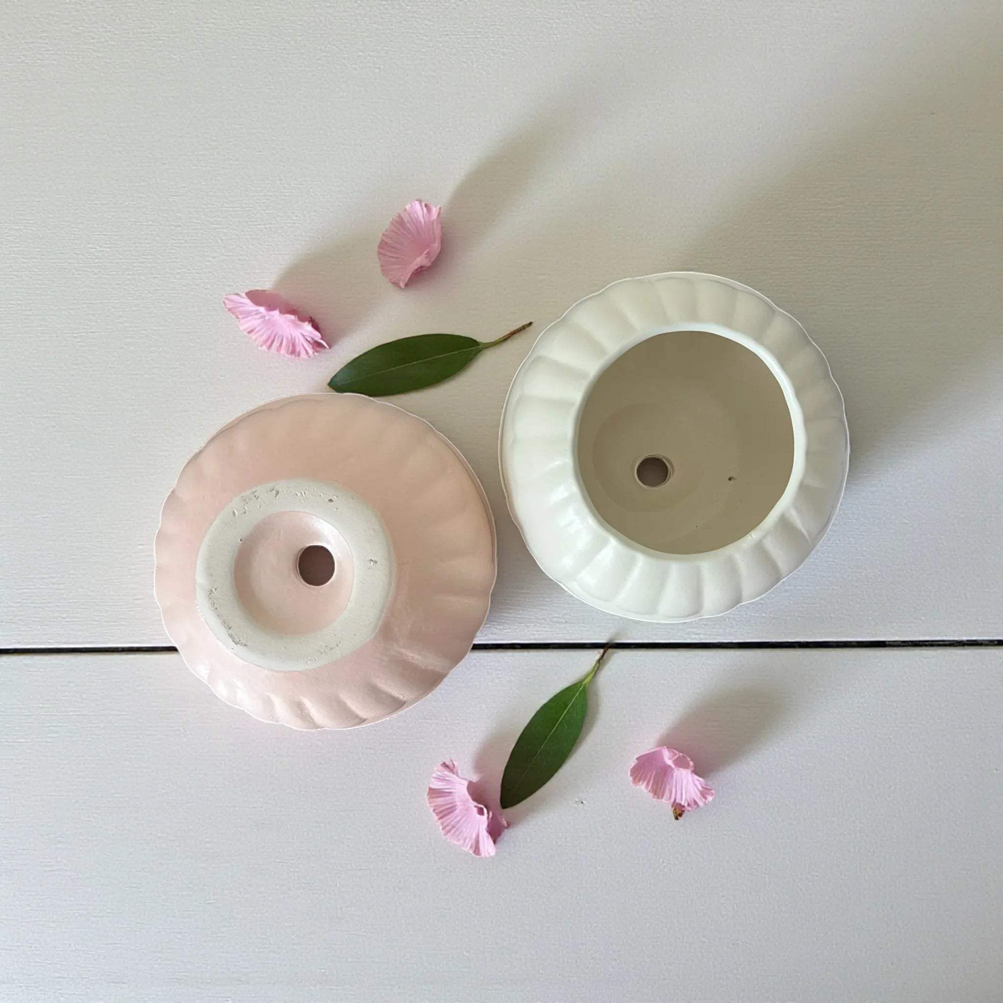Two small ceramic pots with drainage holes for healthy roots.