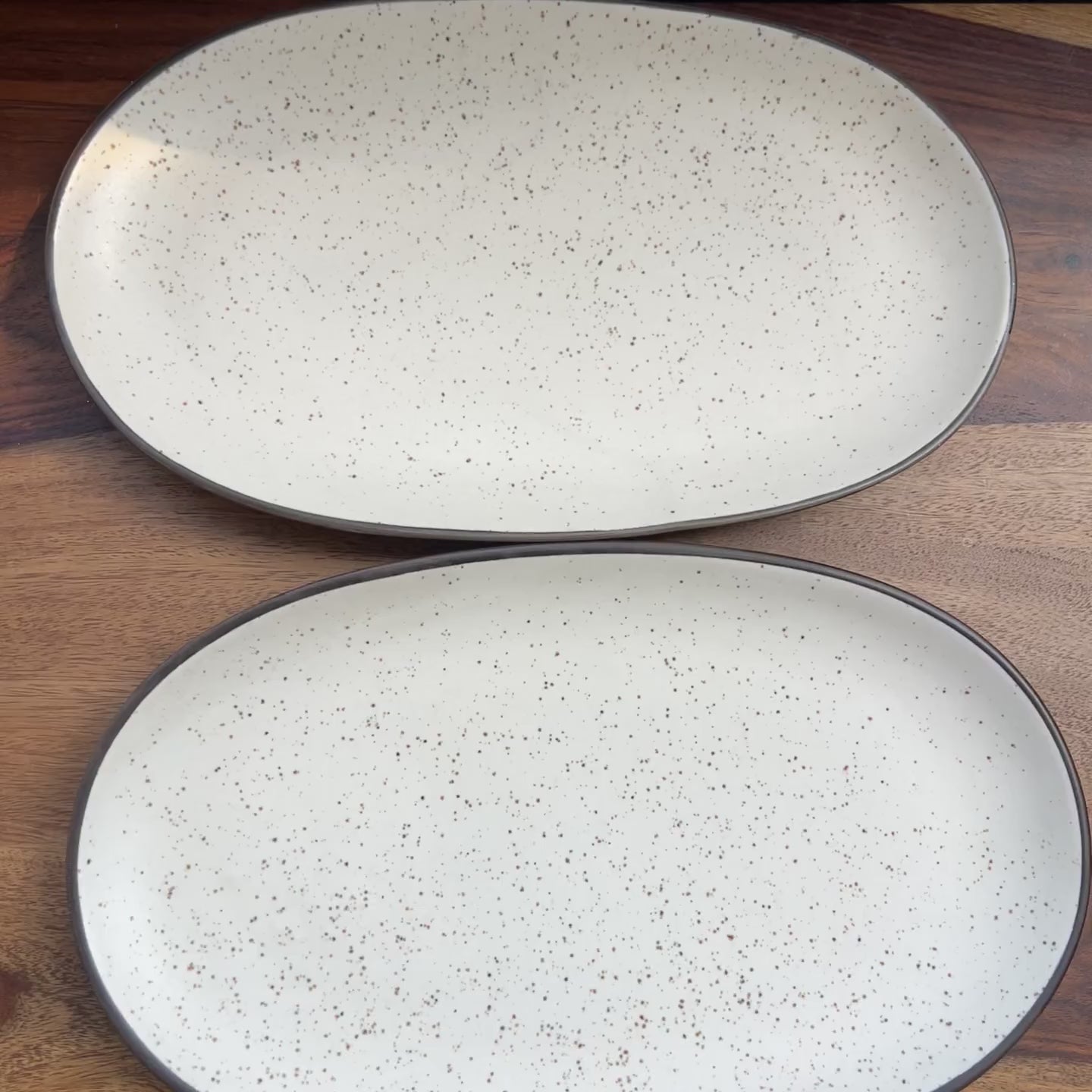 Product video of white speckled ceramic platter with black border.