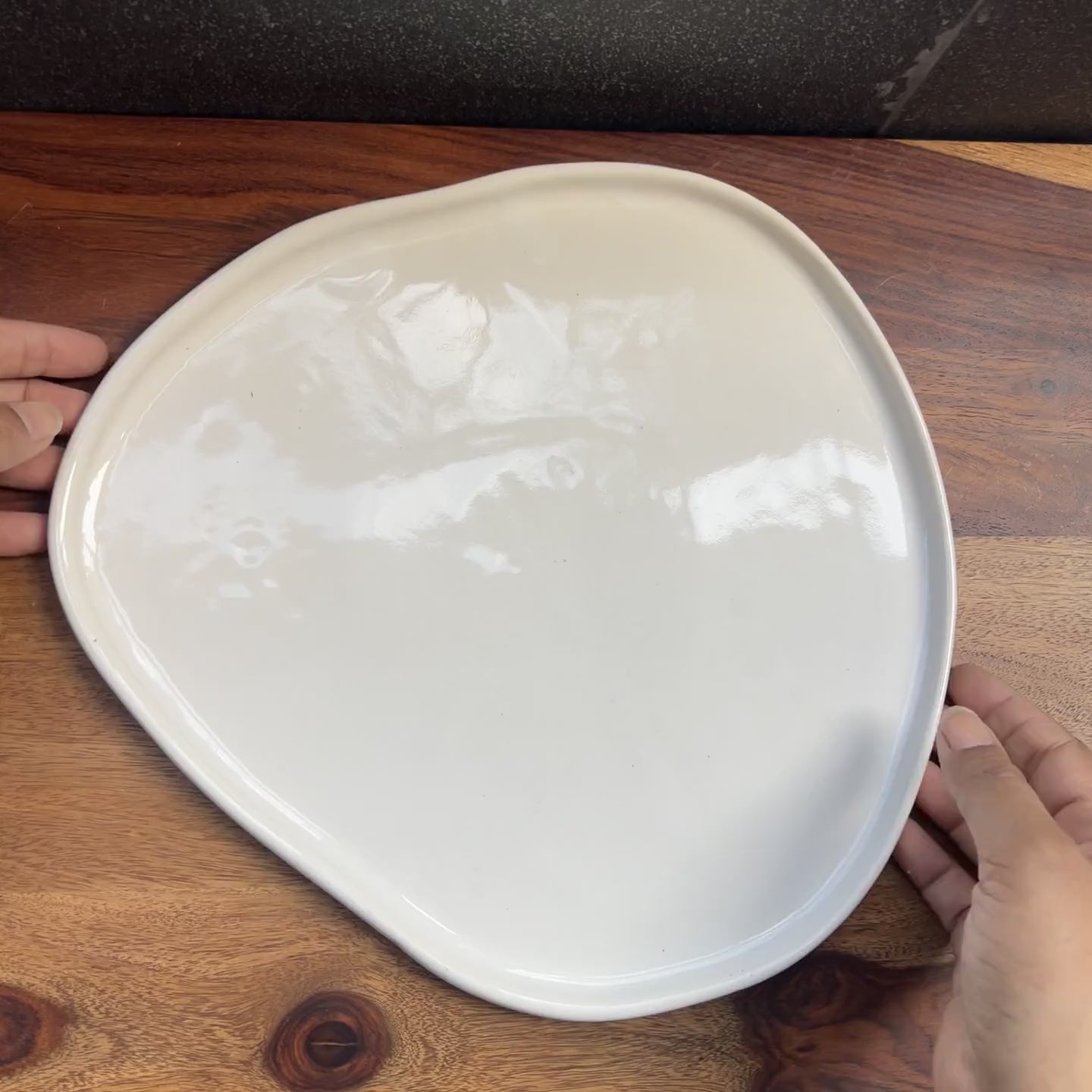 Product video of a white ceramic asymmetrical plate.