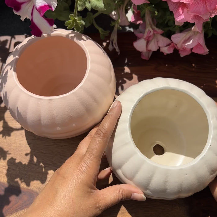 Product video of pastel pebble planters; showing the pink and white matte finish with woven texture.