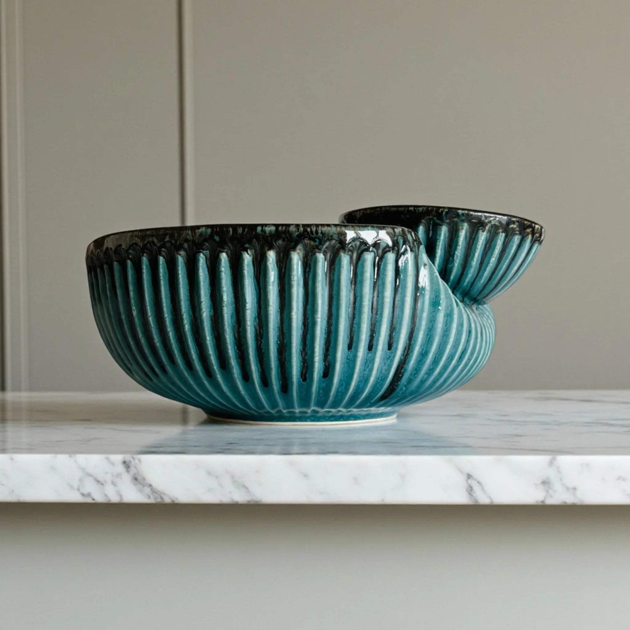 Ribbed texture close-up; handcrafted ceramic ridges finished in a glossy, wave-like ocean blue glaze.