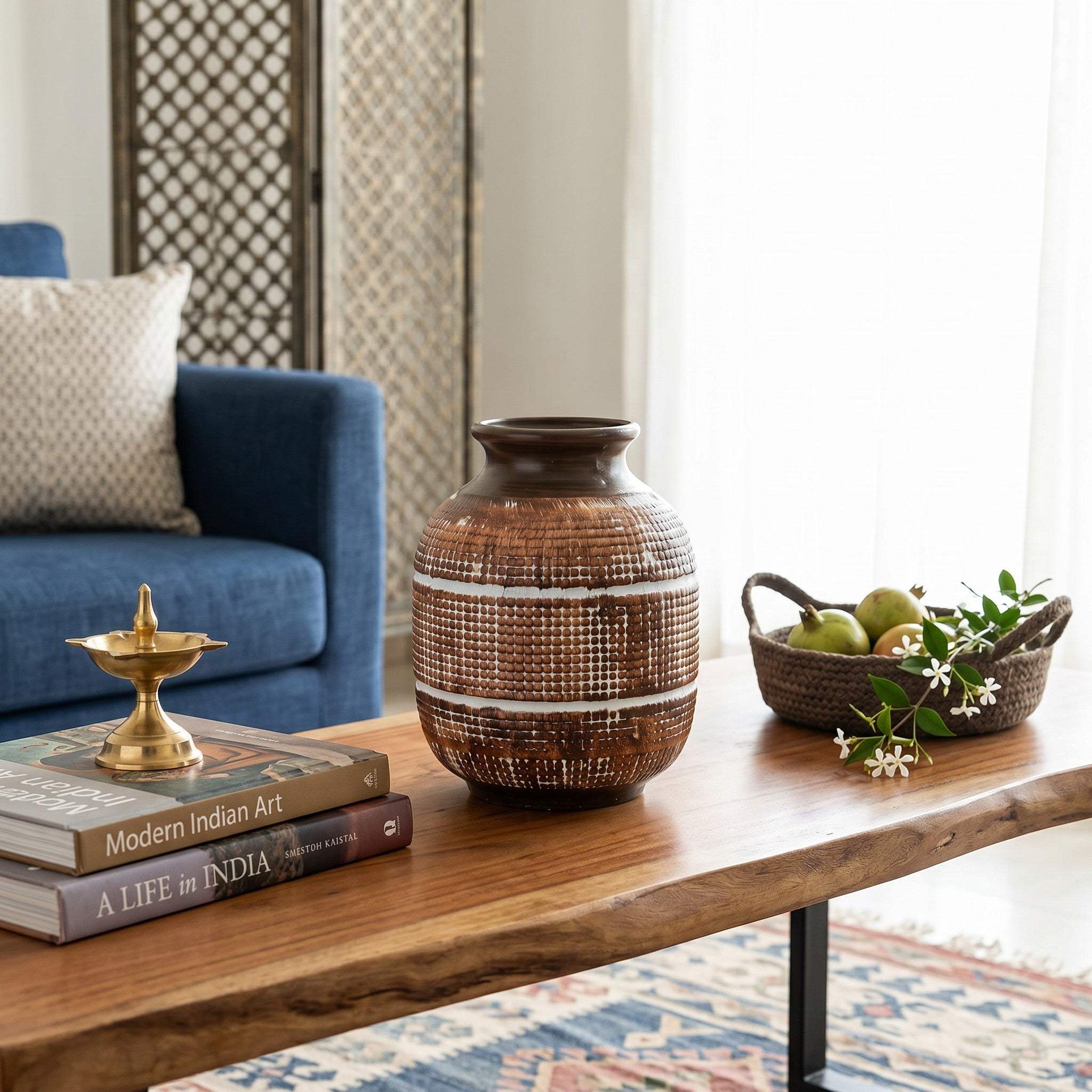 Textured earthy brown flower vase with fresh eucalyptus stems as a center piece layout on an urban Indian home coffee table.