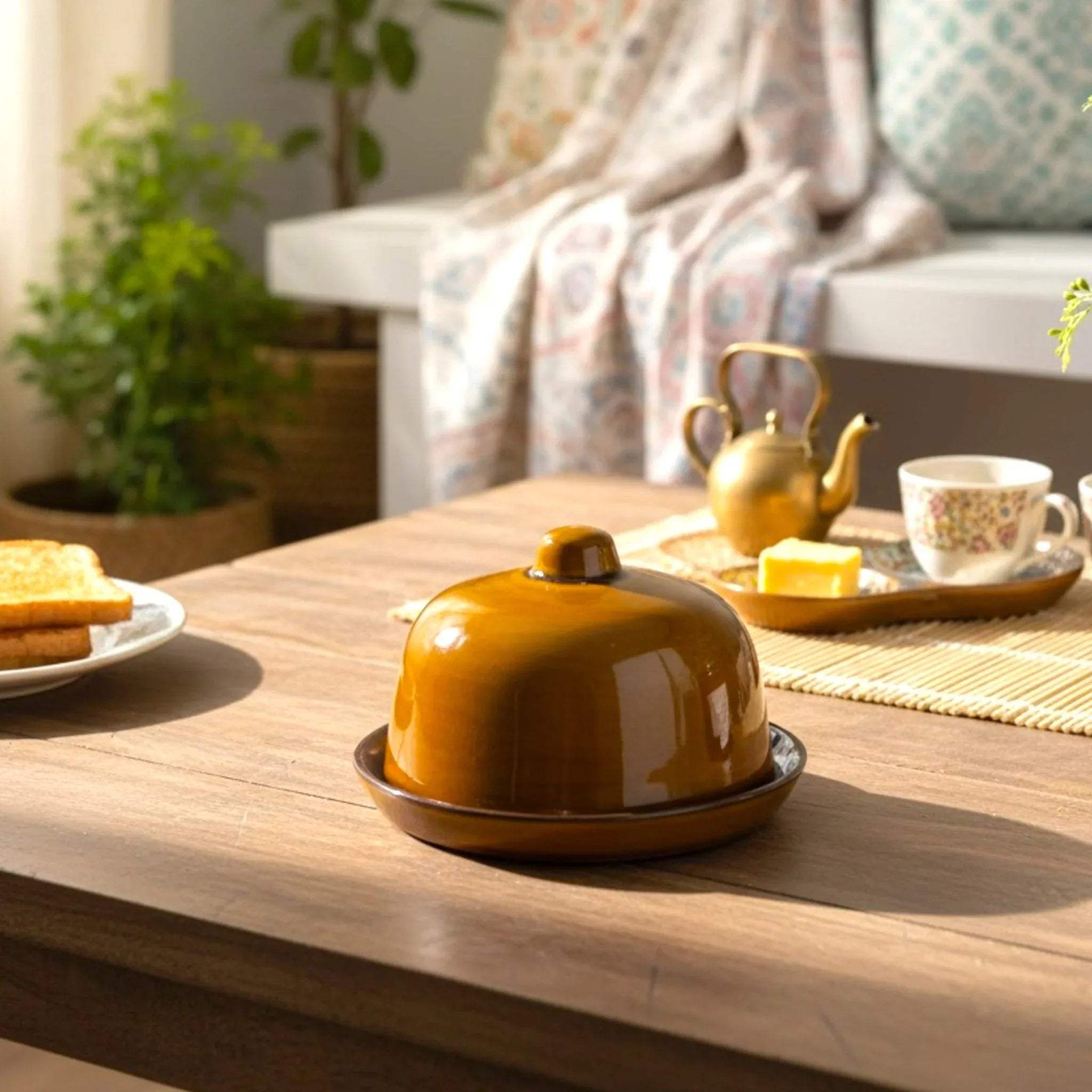 Close-up of smooth variation; high-gloss amber ceramic butter dish with a minimalist dome lid and top handle.