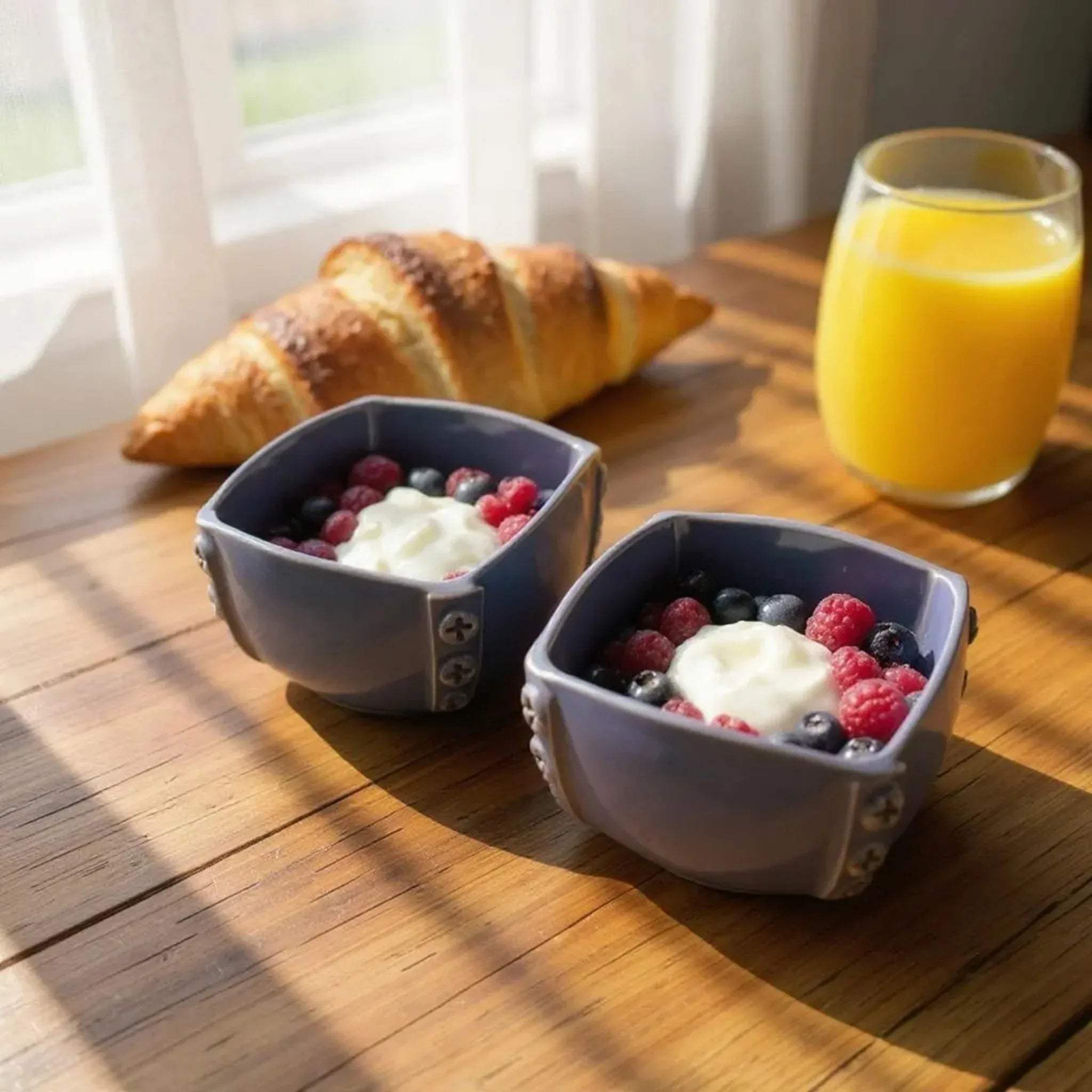 Spring brunch setup; the bowls styled on a wooden table with fresh berries and orange juice.