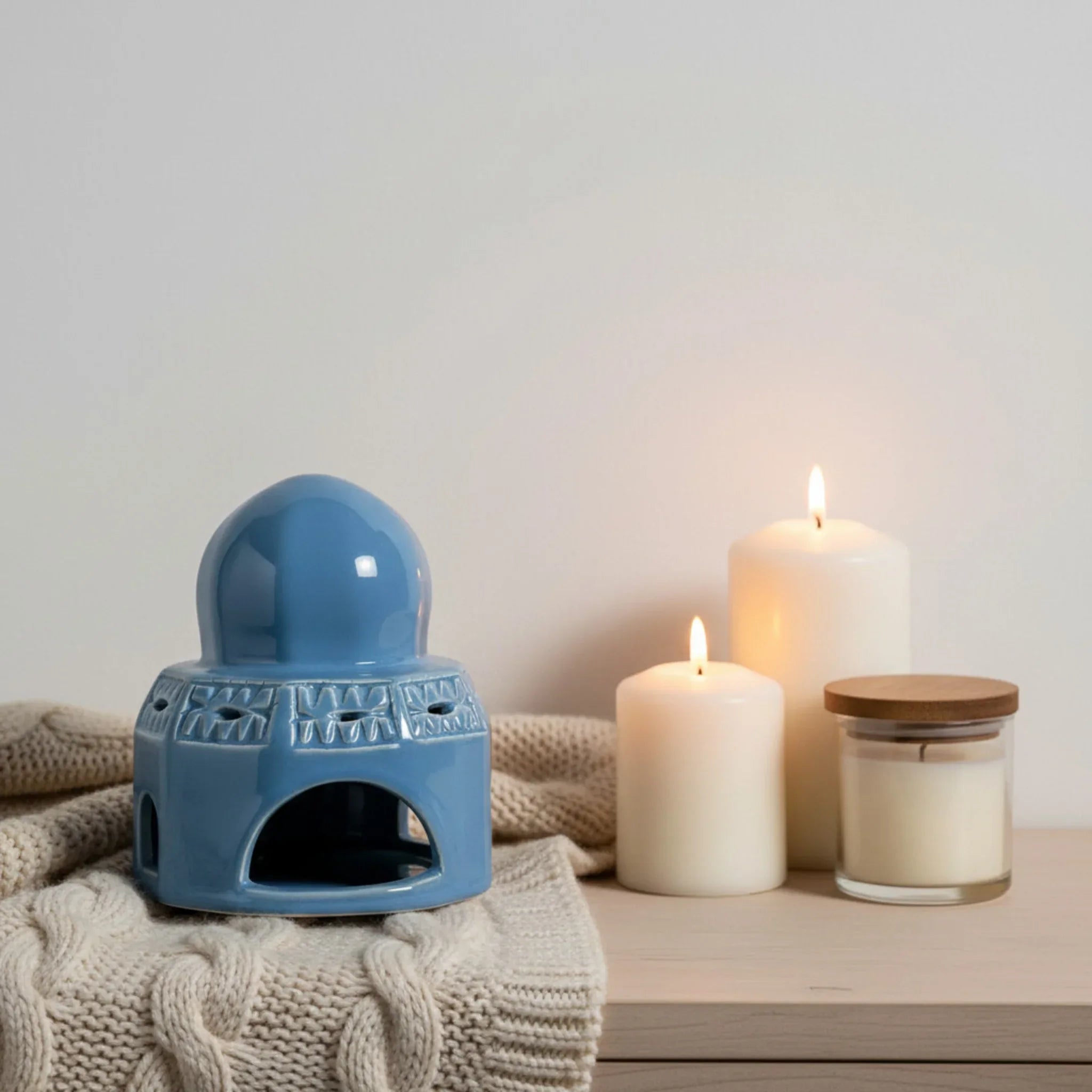 Pinterest inspired corners; Blue ceramic candle holder with candles and blanket on a wooden surface for a cozy vibe.