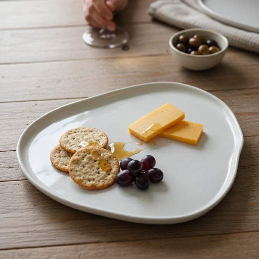 Wabi Sabi Plate; a warm off-white ceramic serving plate with a gently irregular organic silhouette.